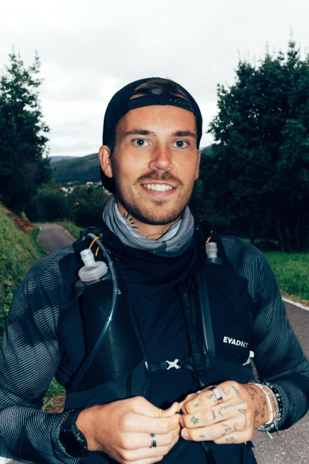 Jonathan Fors on a road in a running vest, hills behind him.